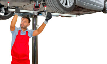 A man measuring a car’s underbody with a measuring tram bar.