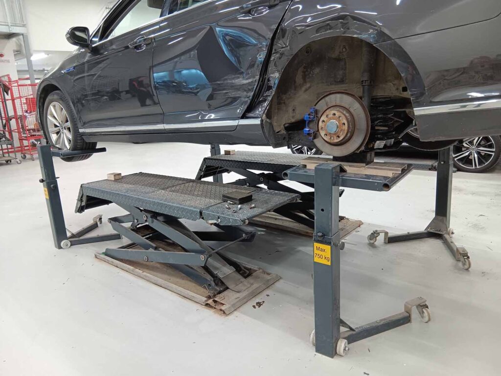 Car supported on Autorobot wheel stands with the rear wheel removed for repair work.