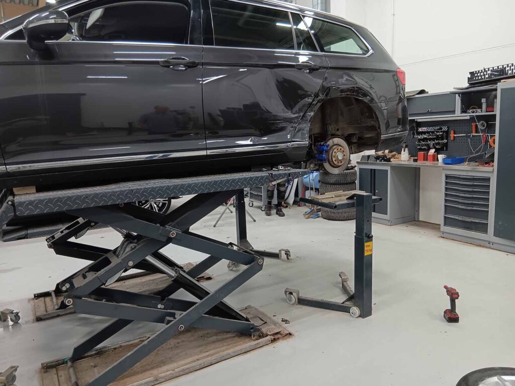 Car raised on a scissor lift with the rear wheel removed and an Autorobot wheel stand positioned below.