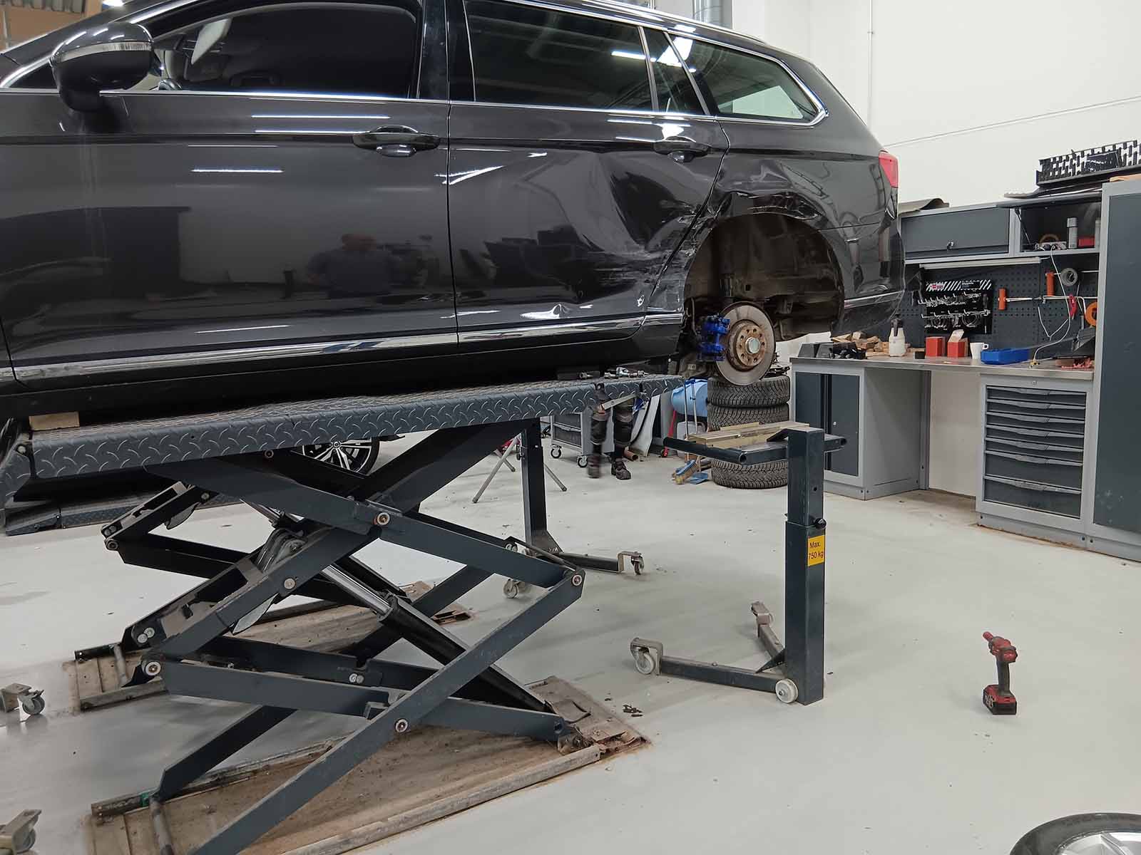 Car raised on a scissor lift with the rear wheel removed and an Autorobot wheel stand positioned below.