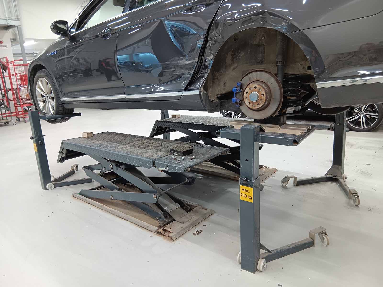 Car supported on Autorobot wheel stands with the rear wheel removed for repair work.